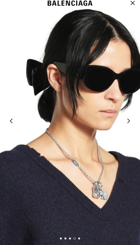 Balenciaga pendant necklace with silver chain and clover charm worn on neckline