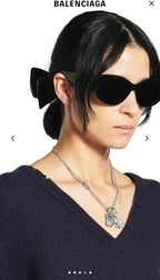 Balenciaga pendant necklace with silver chain and clover charm worn on neckline