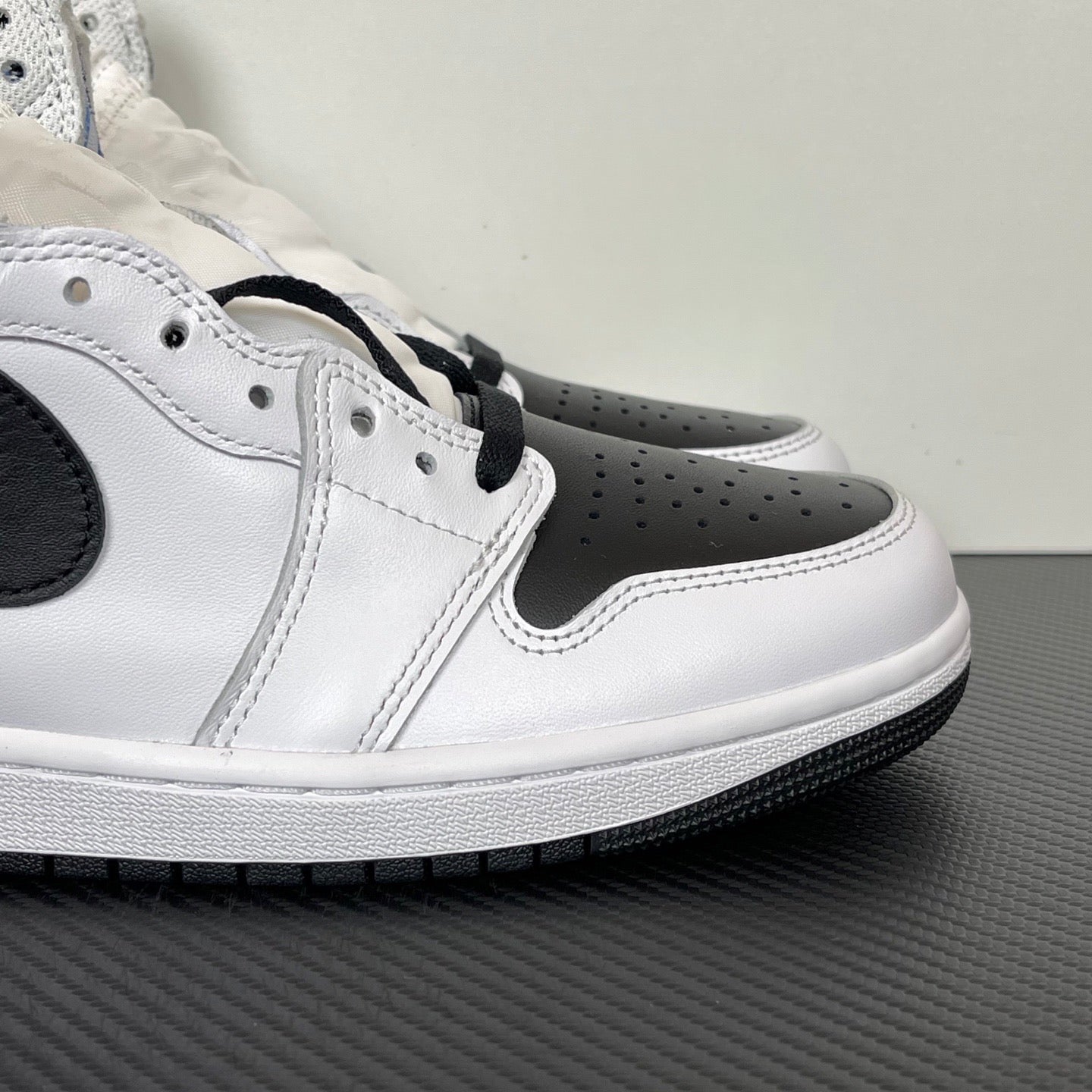 Side view of white and black high-top sneakers with perforated toe and black eyestay