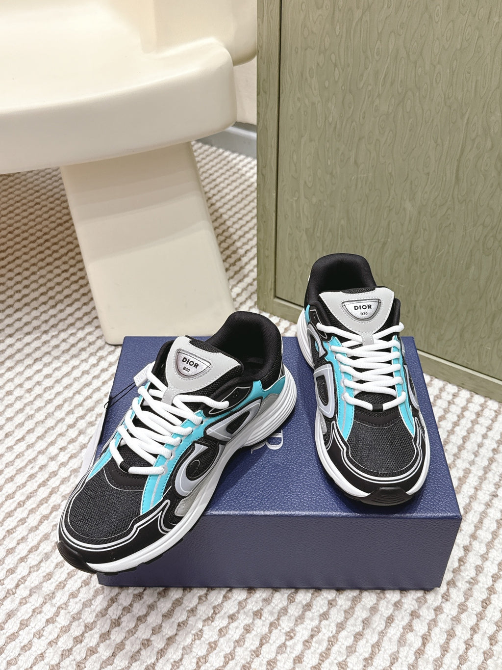 Dior unisex sneakers on box, black mesh upper with turquoise piping and white laces