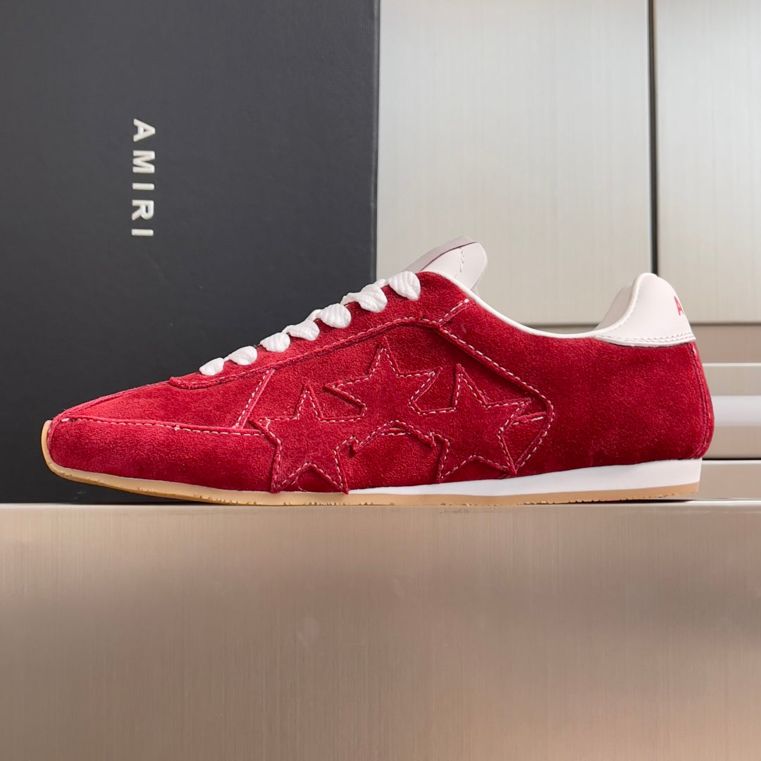 Red suede Amiri low-top sneakers with white laces, star pattern on side