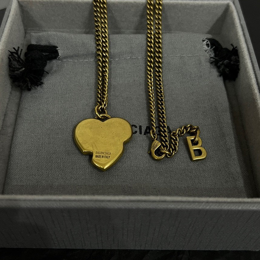 Gold heart pendant necklace with clasp and small letter charm in box tray.