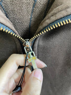 Metal zipper pull on brown hoodie with blue cord trim