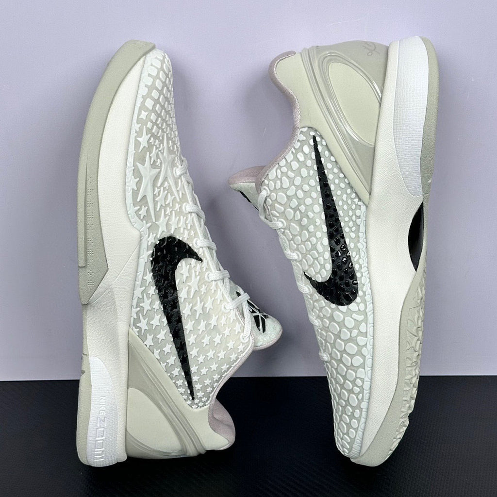 Low-top sneakers front quarter view, star-textured white upper, black swoosh
