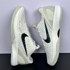 Low-top sneakers front quarter view, star-textured white upper, black swoosh