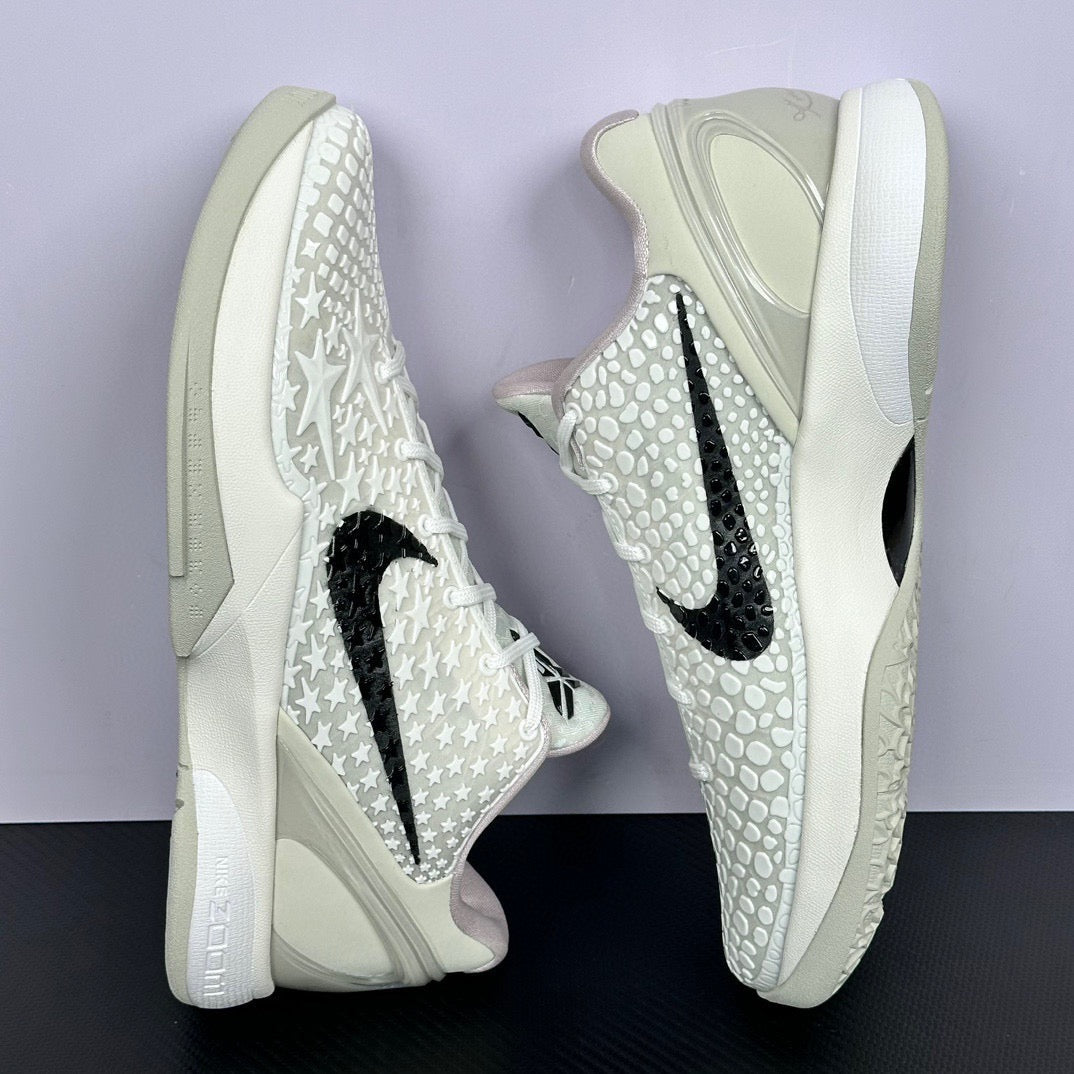 Low-top sneakers front quarter view, star-textured white upper, black swoosh