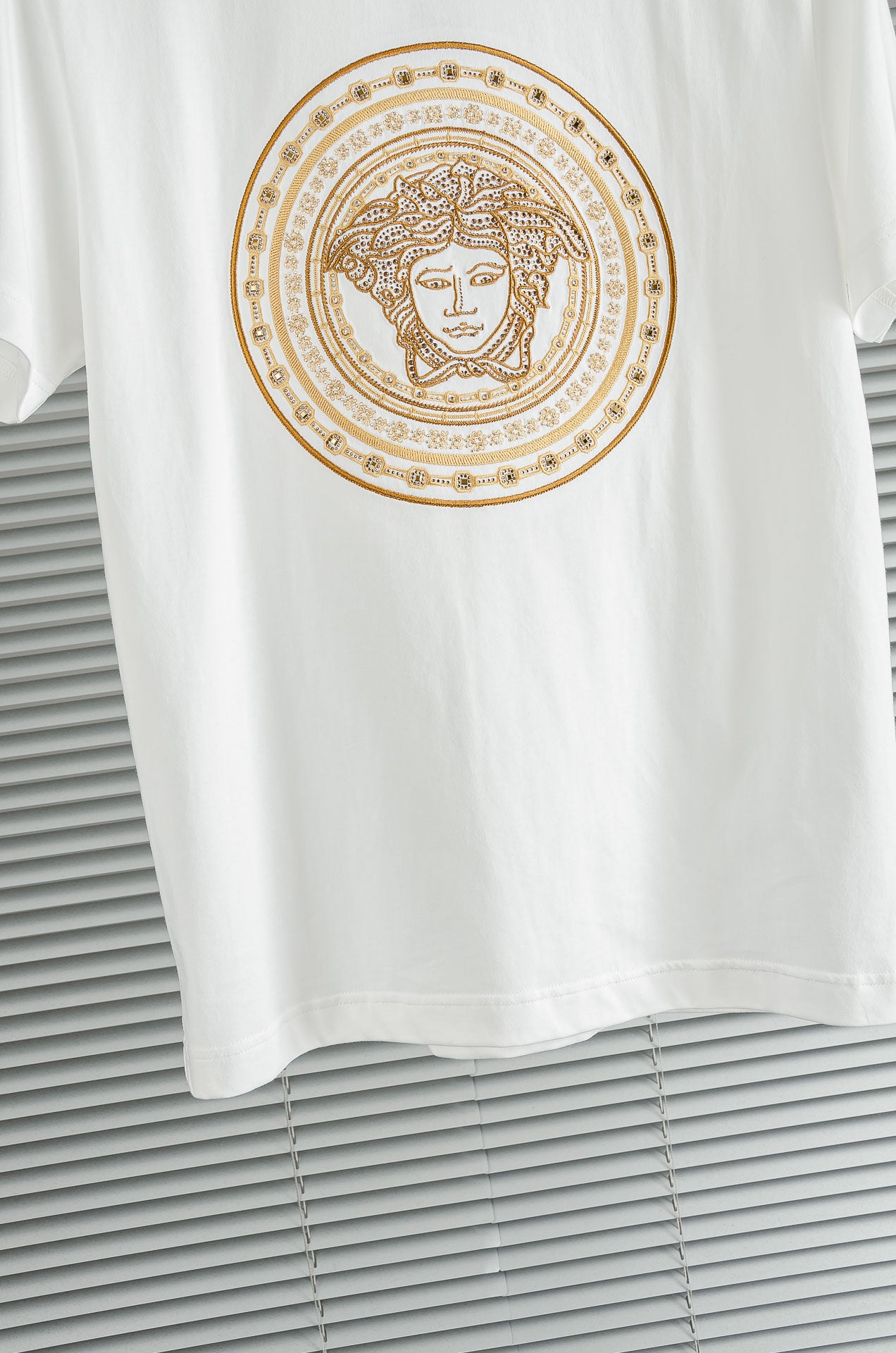 Versace white T-shirt close-up of gold Medusa circular chest graphic