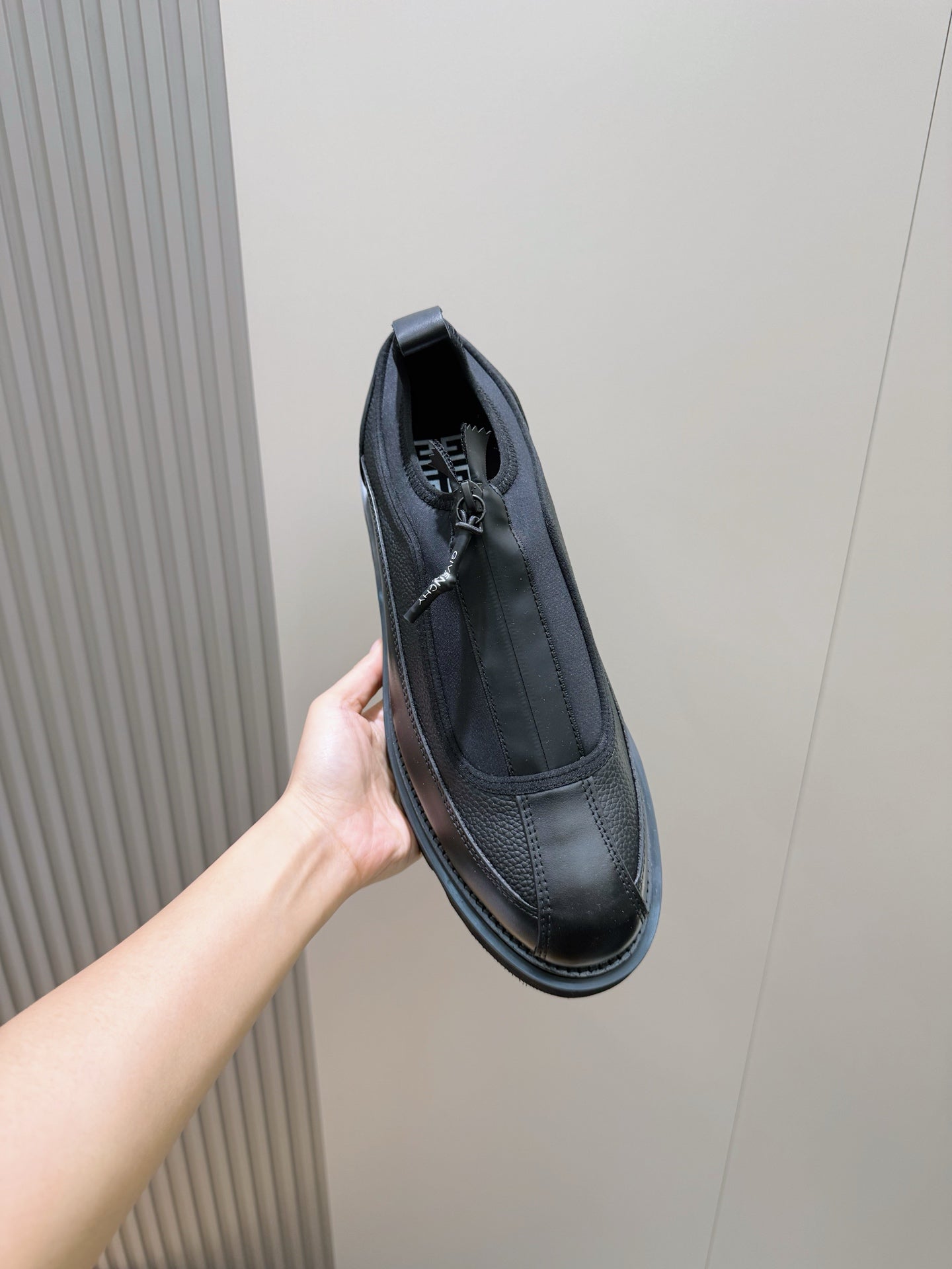 Lace-up leather shoe on hand, dark upper with stitched details and thick sole