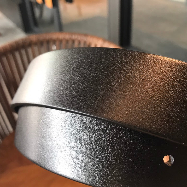 Black leather belt close-up with gold-tone rivet and textured finish
