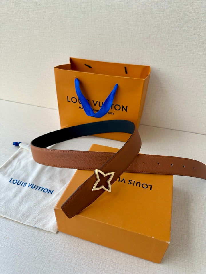 Tan leather belt with dark navy star buckle, placed on a Louis Vuitton shopping box
