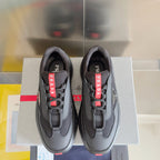 Prada unisex sneakers, front view: dark gray upper with red PRADA tongue straps