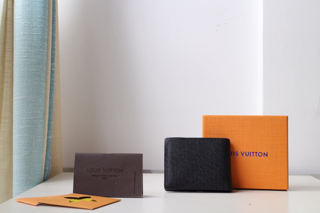 Louis Vuitton small black textured leather pouch with front LV emblem and curved edge