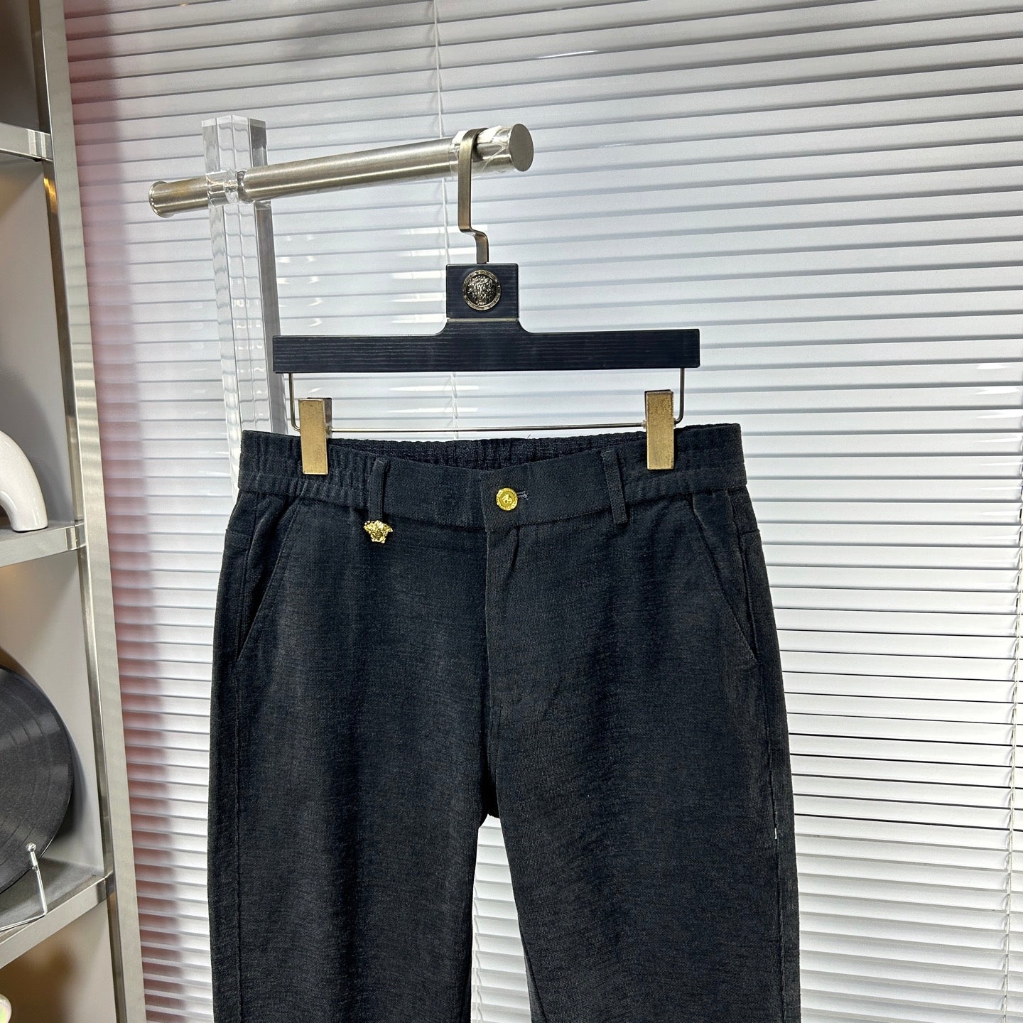Dark denim pants close-up: elastic waistband with gold button and belt loops