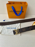 Dark monogram belt with gold V-shaped LV buckle in rhinestones, flat strap.