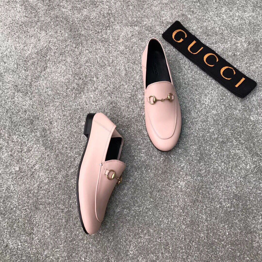Pair of pink Gucci loafers with gold-tone bit detail, one shoe slightly turned