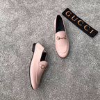 Pair of pink Gucci loafers with gold-tone bit detail, one shoe slightly turned