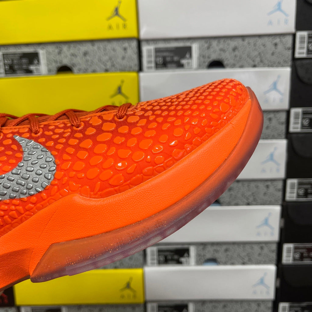Orange sneaker side profile with gray swoosh and smooth strap detail