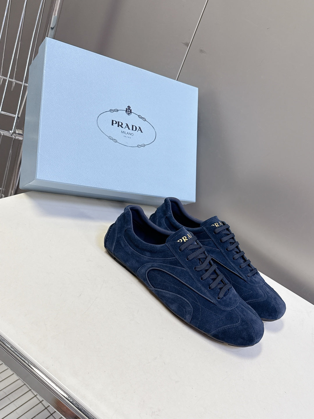 Blue suede sneakers, lace-up front with Prada-branded tongue.