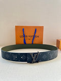 Louis Vuitton belt with dark monogram strap and silver-tone LV buckle, flat view.