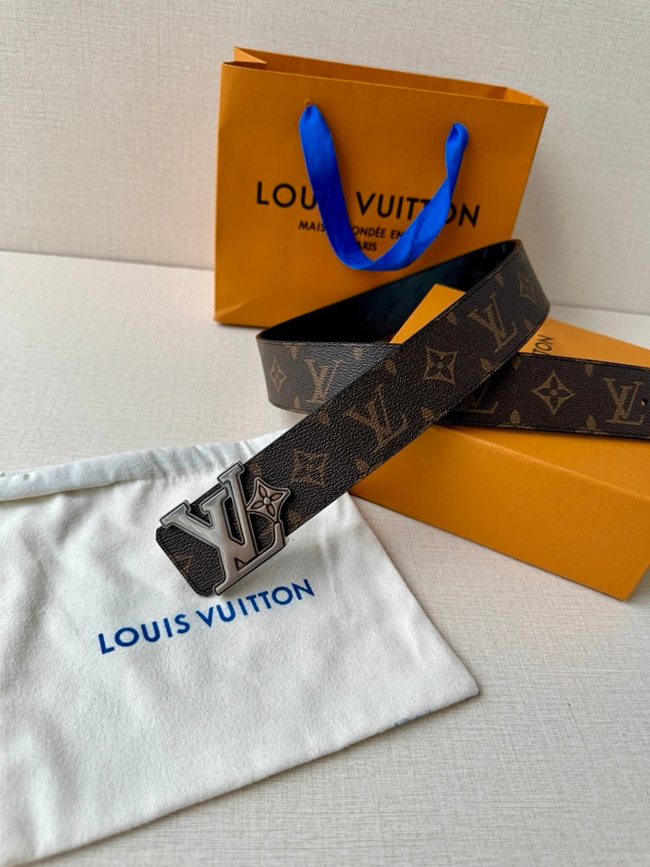 Louis Vuitton monogram belt with dark strap and gold logo buckle on white pouch