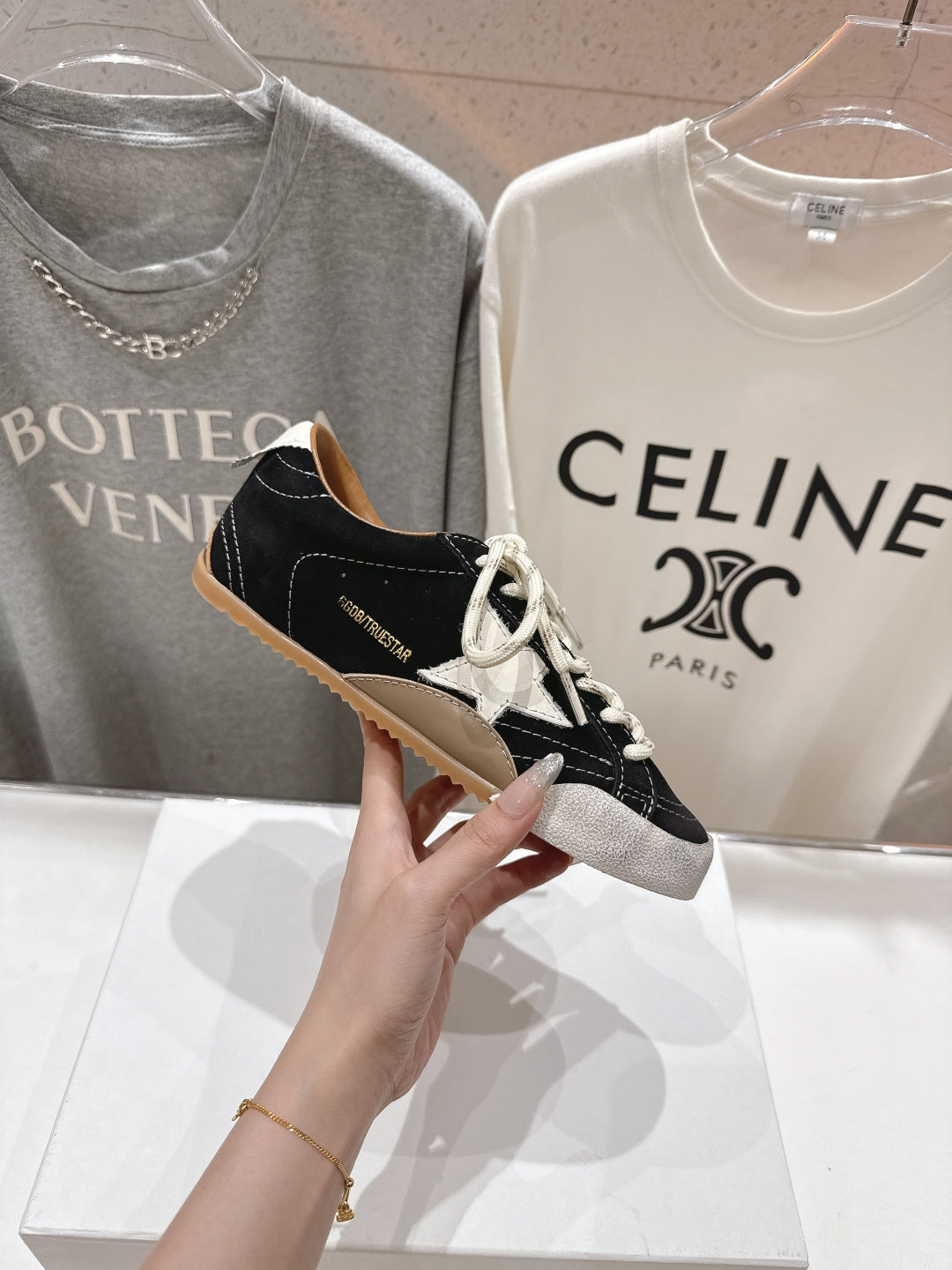 Single black and off-white low-top sneaker held up, with white laces and textured sole.