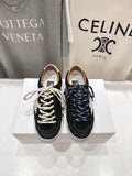 Low-top sneakers in black and off-white, with white and navy laces on a display box.