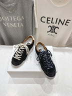 Pair of black and off-white low-top sneakers with white and navy lace-up details.