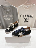 Black and off-white lace-up low-top sneakers set, shown from the front on display boxes.