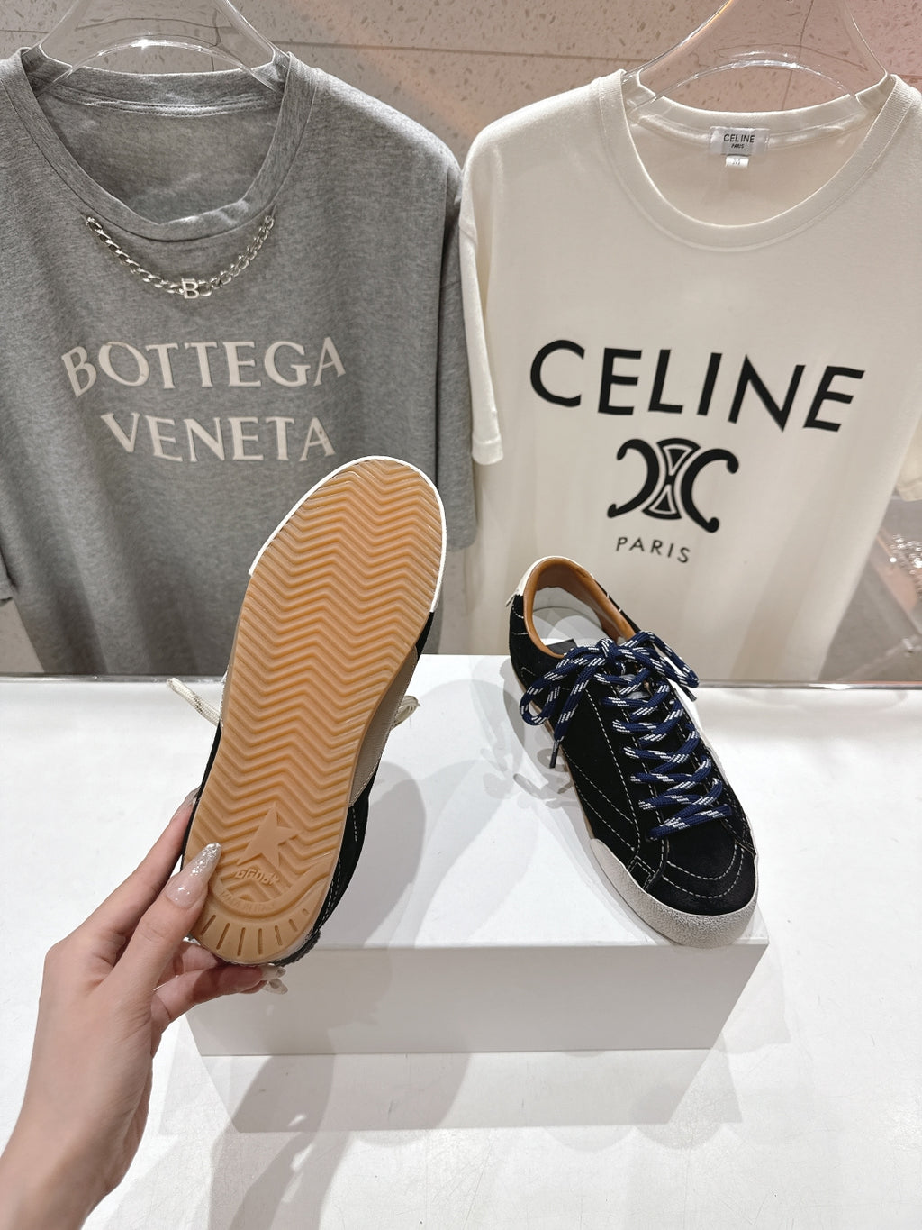 Outsole view of a low-top sneaker, with a second black and off-white shoe on display.