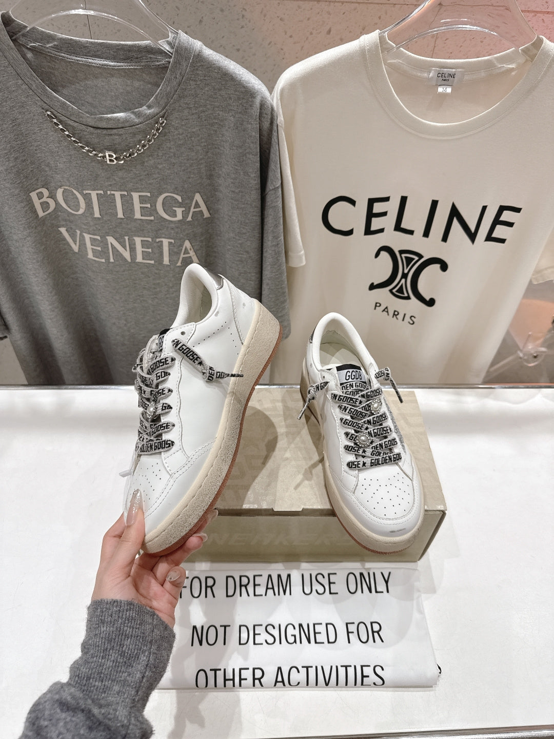 White low-top sneakers with black graphic laces and distressed side panels