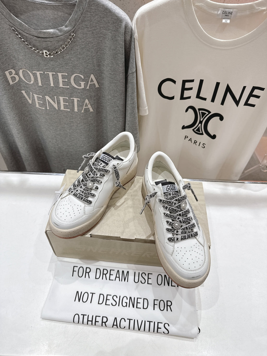 White low-top sneakers with black text-style panels and lace-up front