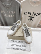 White low-top sneakers with black text-style panels and lace-up front