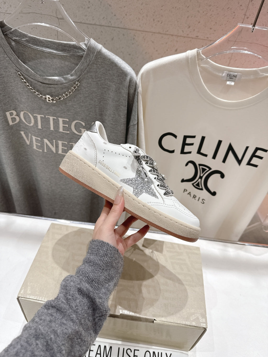 White low-top sneakers with black graphic laces and silver glitter heel detail