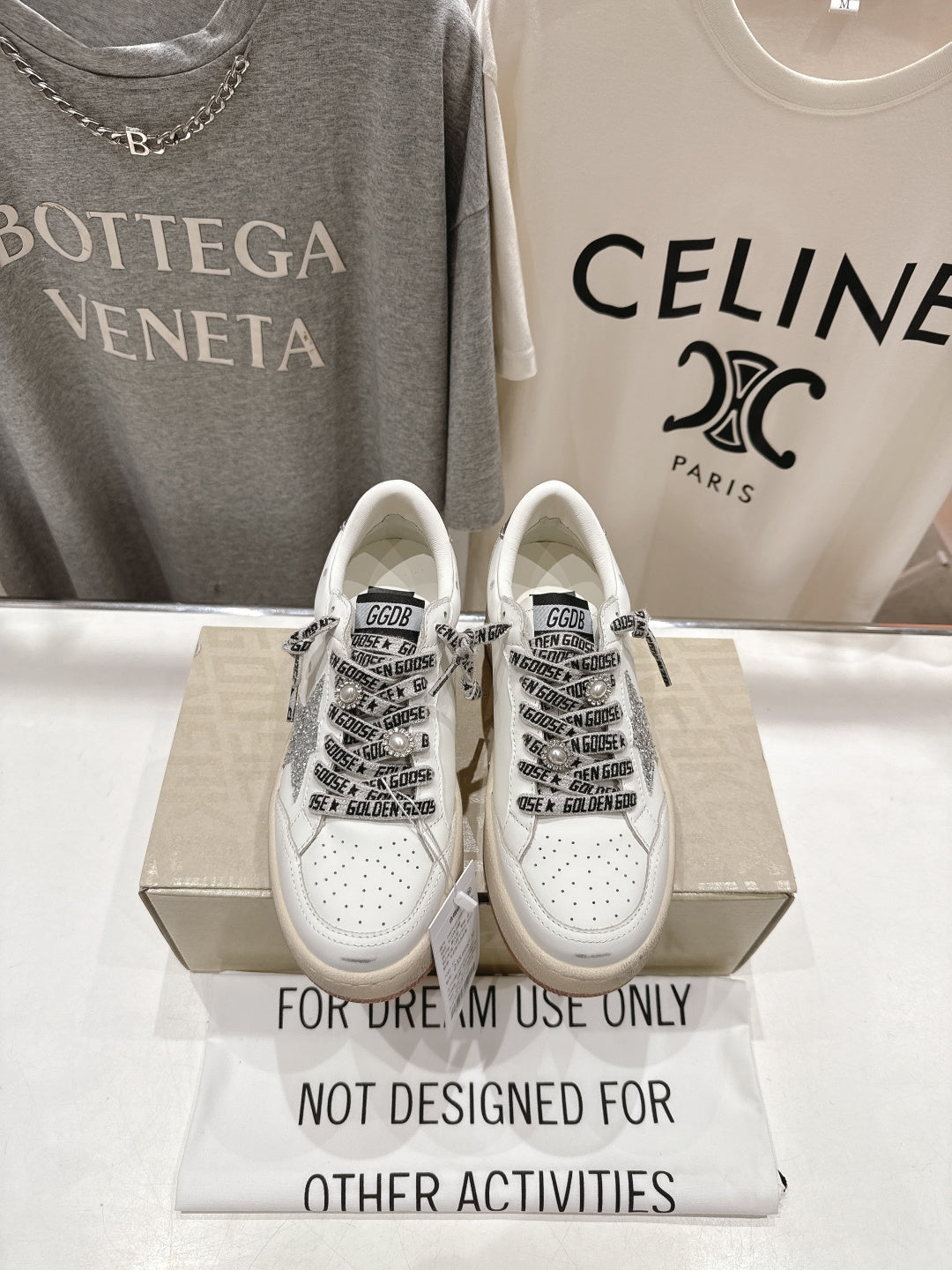 White low-top sneakers with black graphic laces and perforated toe