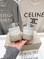 White low-top sneakers with metallic gray logo heel and perforated toe