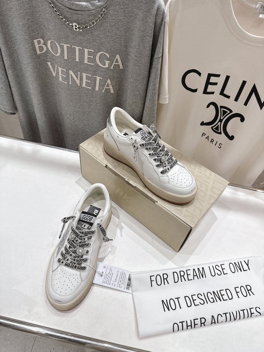 White low-top sneakers on display with black text-style lace panels