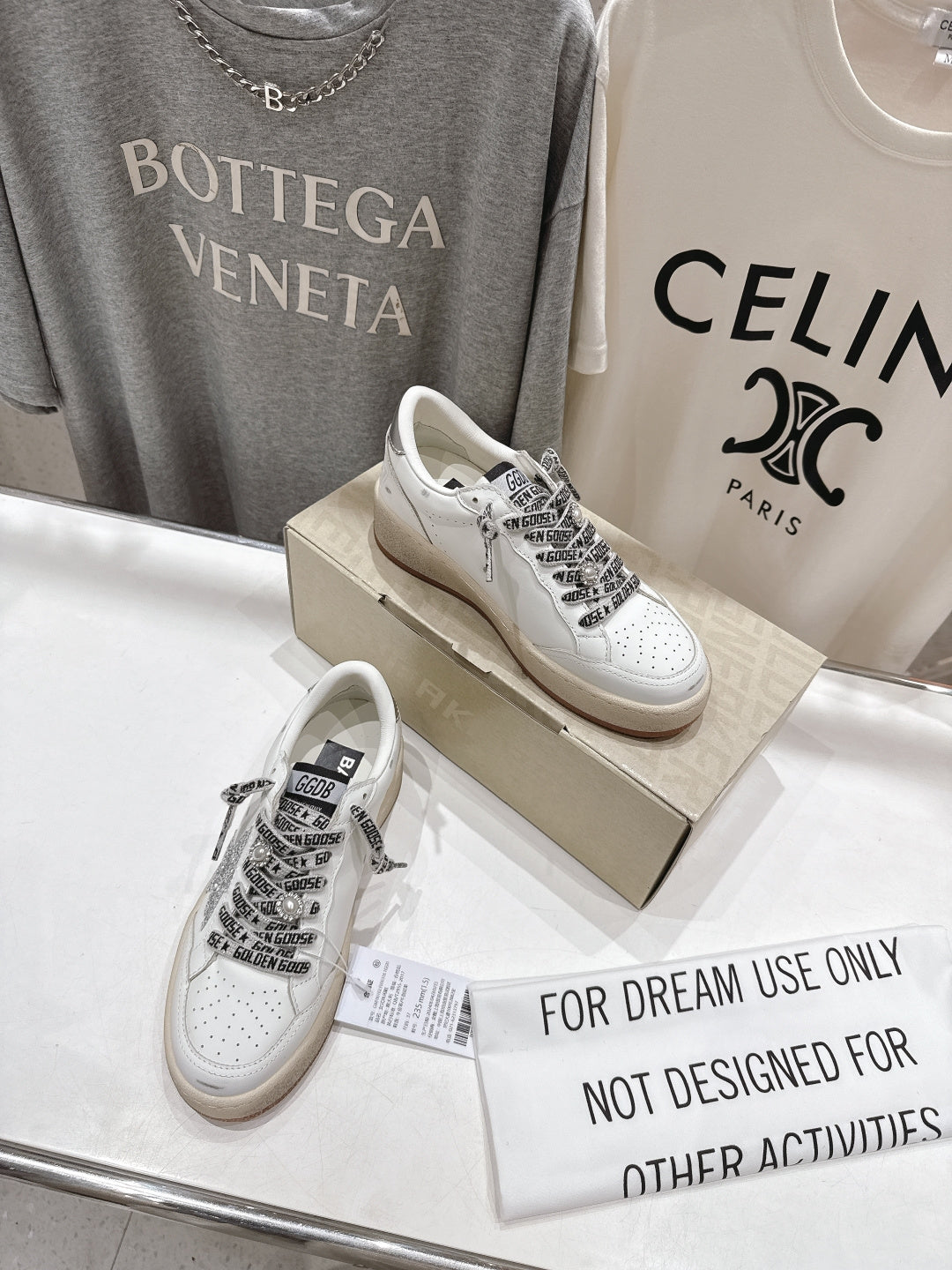 White low-top sneakers on display with black text-style lace panels
