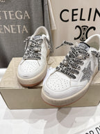 Pair of white low-top sneakers with black graphic laces and perforated toe