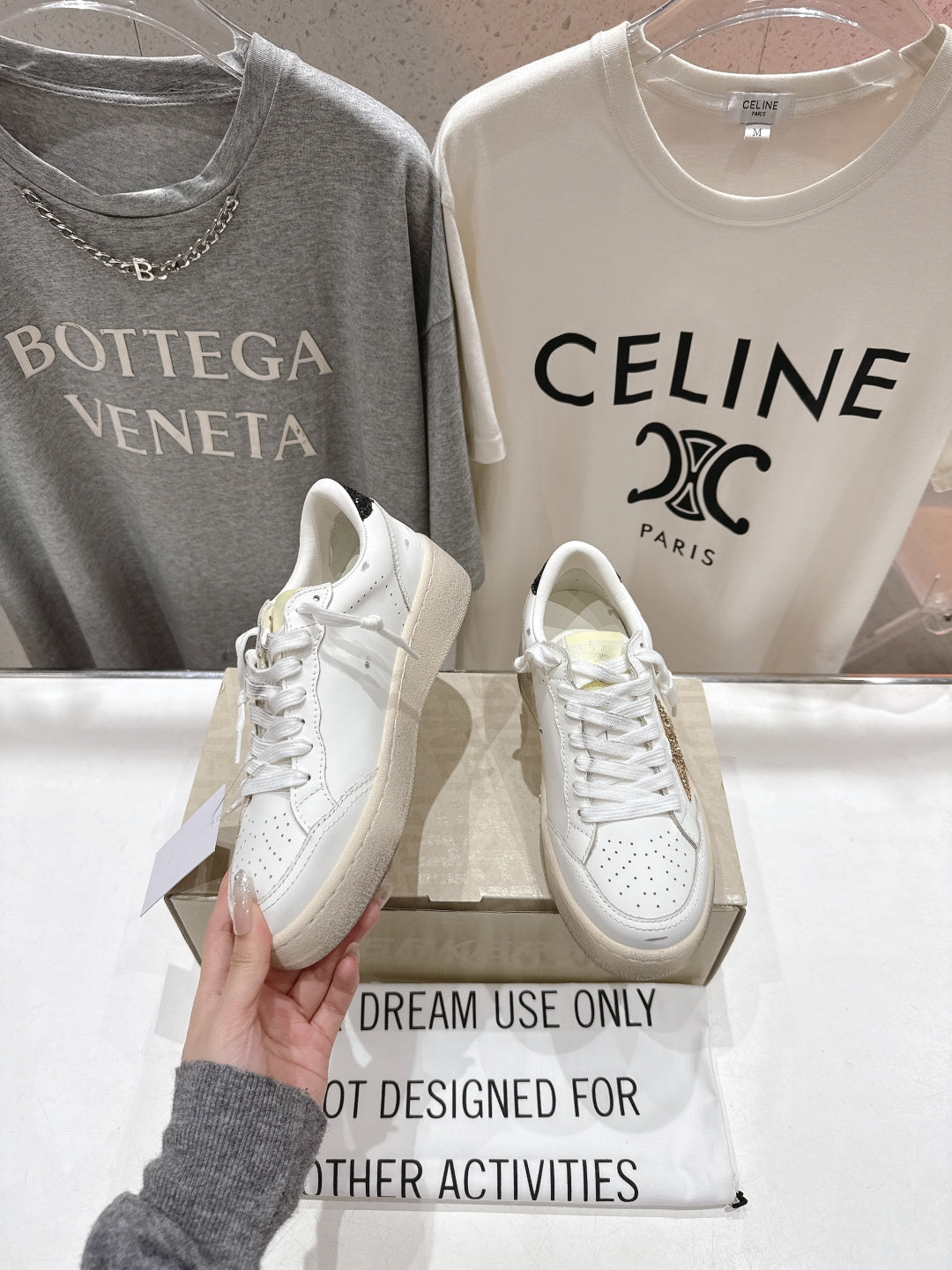 White lace-up sneakers held in hand, toe and laces visible