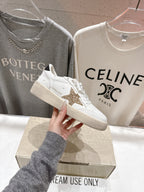 White lace-up sneakers with gold star patch, side view