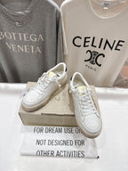 White lace-up sneakers on a box, side view with perforated toe