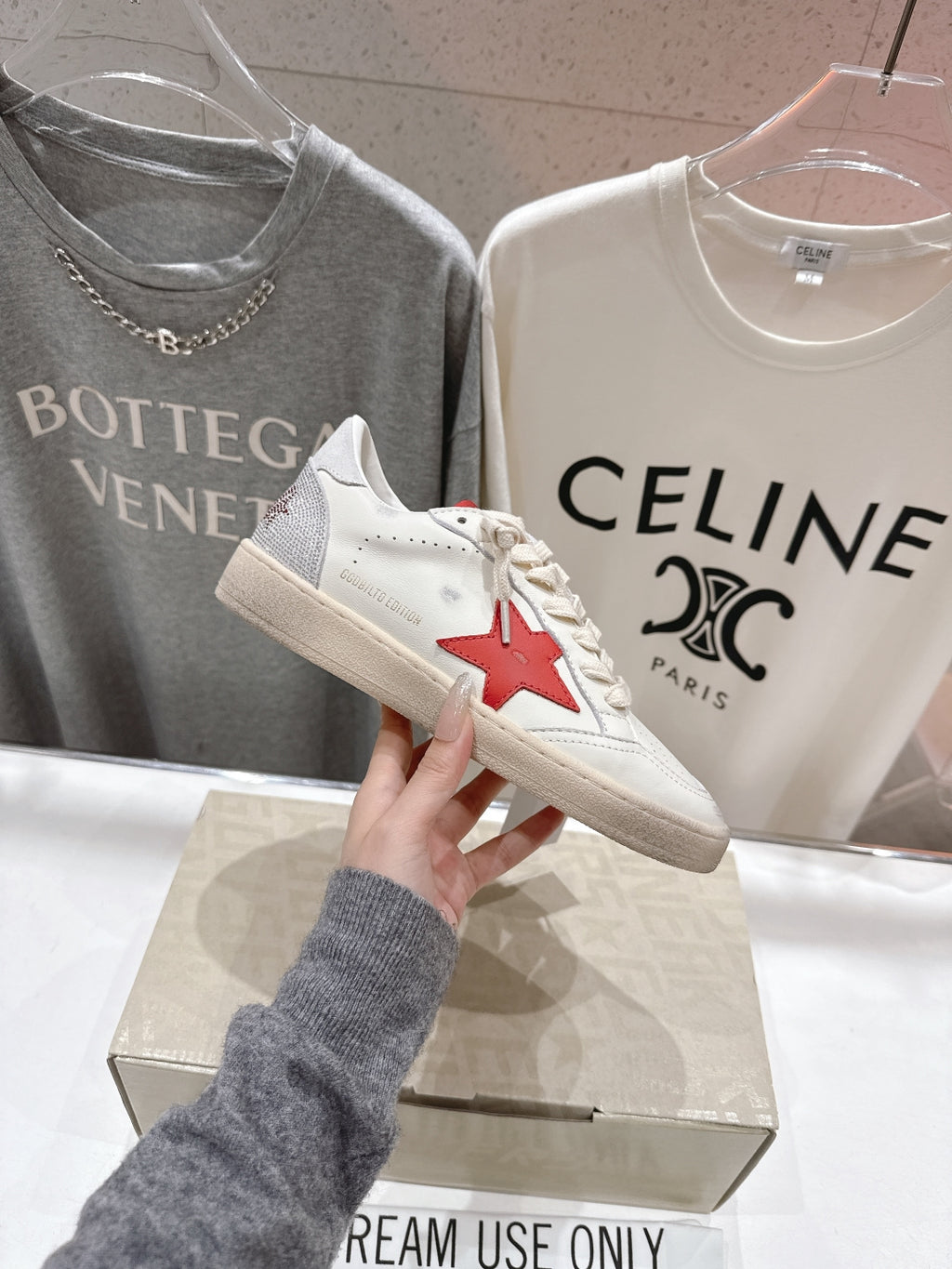 White lace-up low-top sneakers with red star patch on side, on display box