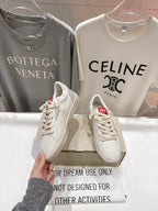 White lace-up low-top sneakers with perforated toe details, held up for viewing