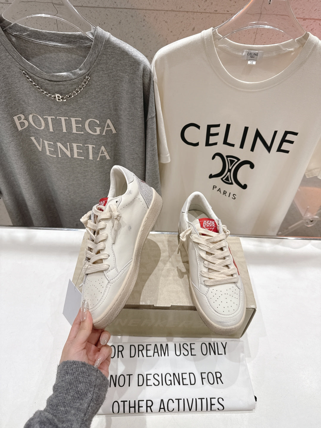 White lace-up low-top sneakers with perforated toe details, held up for viewing