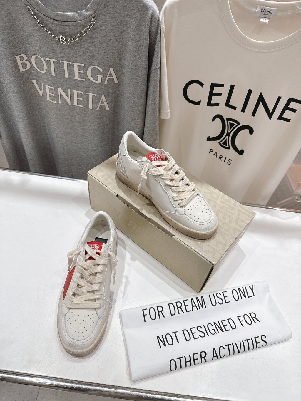 White lace-up low-top sneakers with red heel detail on display box