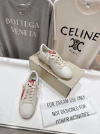 White lace-up low-top sneakers with red heel detail on display box