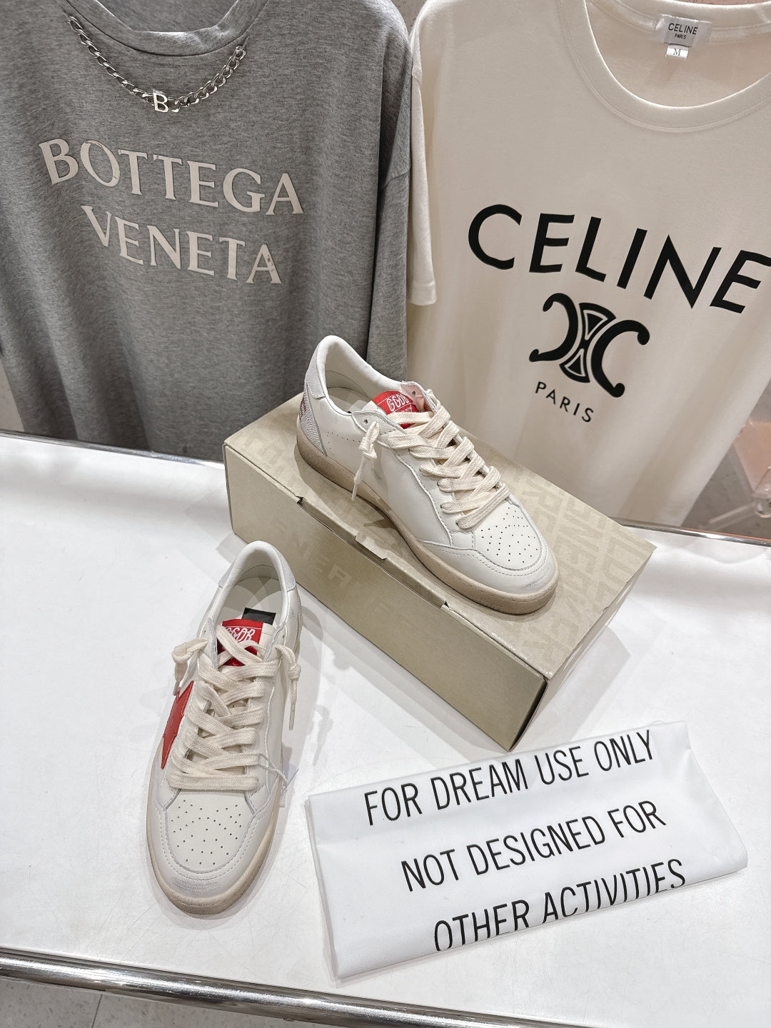 White lace-up low-top sneakers with red heel detail on display box