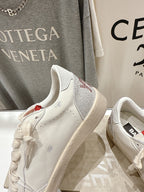 Close-up of white lace-up low-top sneaker with perforated paneling and red accent