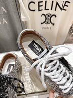 Silver sequin sneaker with 'TRUE' label and white laces, close-up