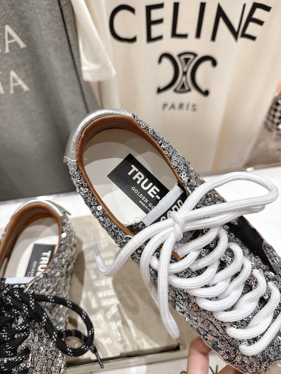 Silver sequin sneaker with 'TRUE' label and white laces, close-up